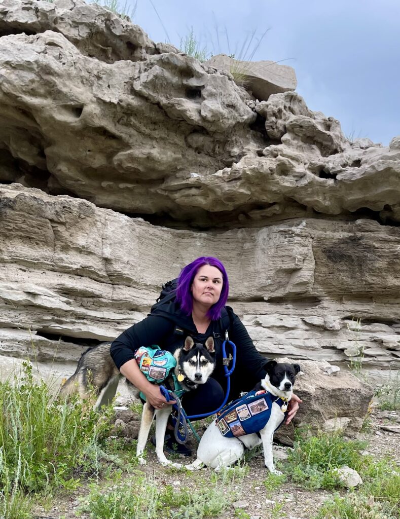 woman with tow dogs in front of rock formations